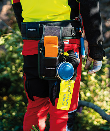 Gros plan sur un travailleur forestier portant une ceinture  outils avec coins, mtre enrouleur, spray et autres accessoires.