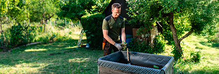 Homme en tenue de travail plantant dans une jardinire surleve par temps ensoleill.