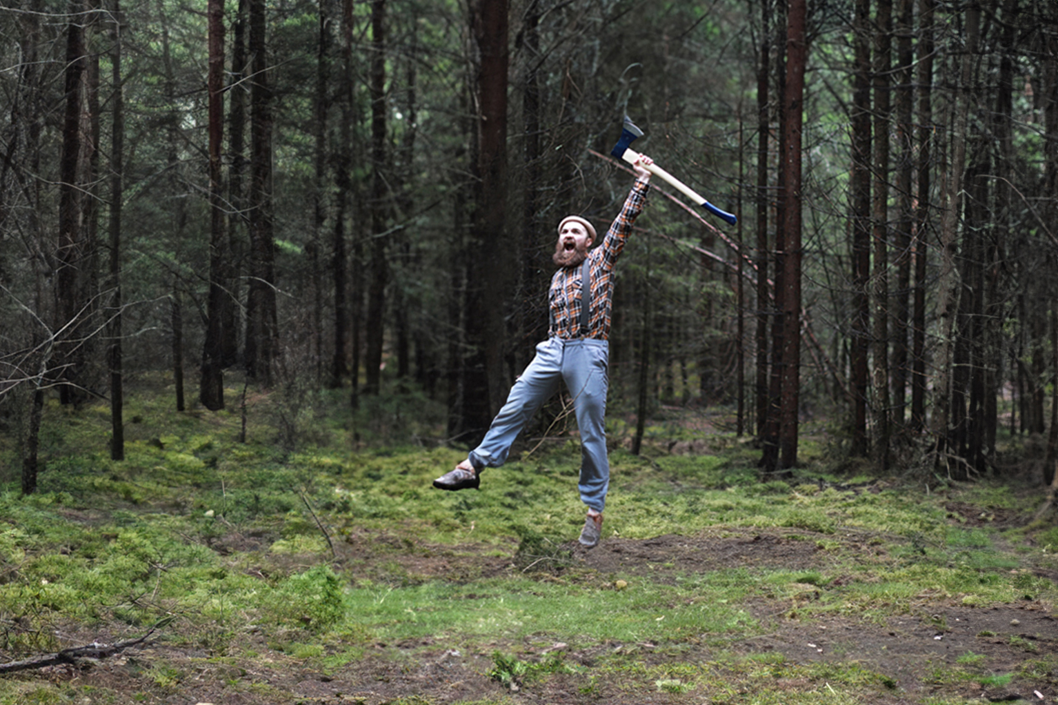 Homme barbu saute de joie en l’air dans une fort en tenant une hache  tte bleue au-dessus de lui.